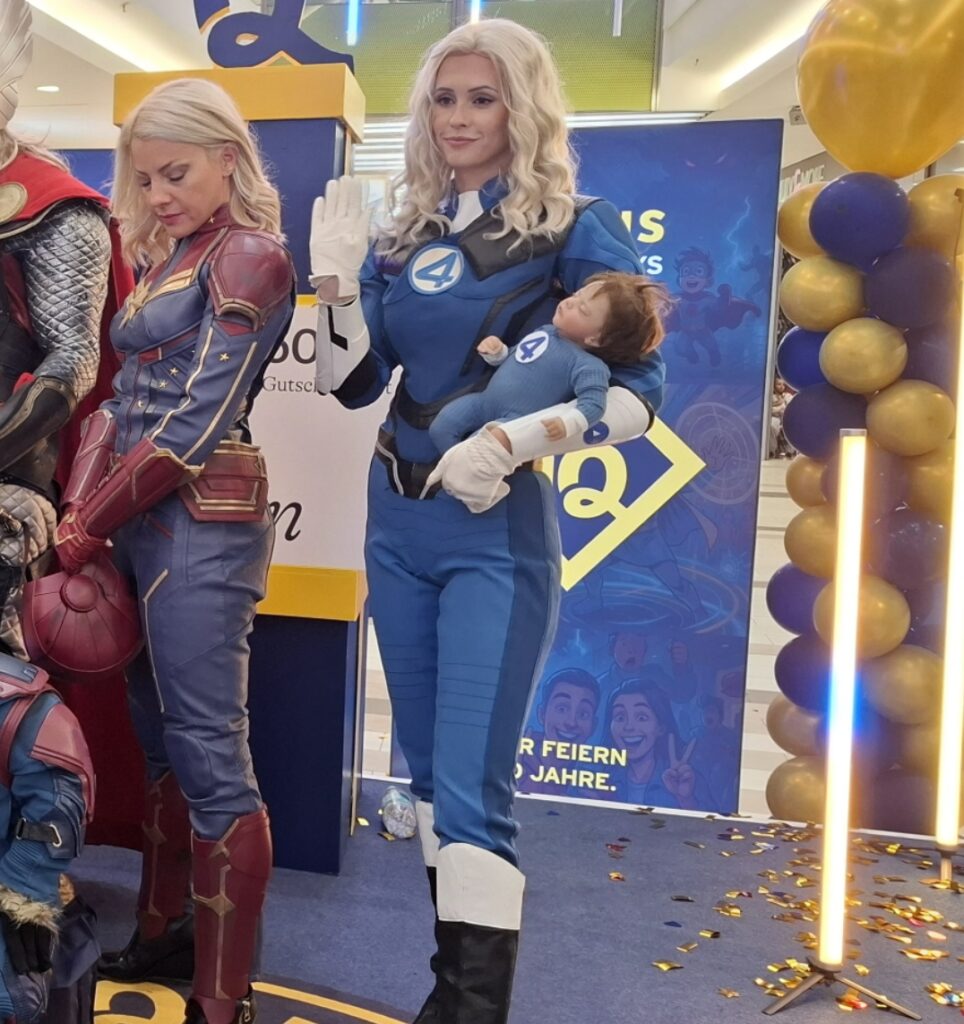 sue strom aus fantastic four mit ihrem baby auf dem arm in pose